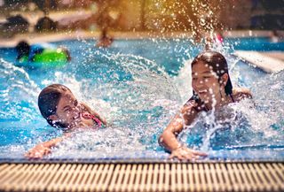Sisters splashing in a swimming pool at one of the many caravan parks reopening.