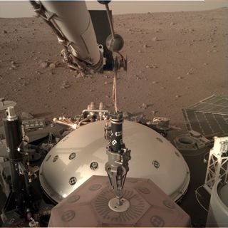 NASA's InSight Mars lander holds its seismometer-suite instrument with its claw-like grapple on Dec. 15, 2018. InSight is preparing to place the instrument on the ground.