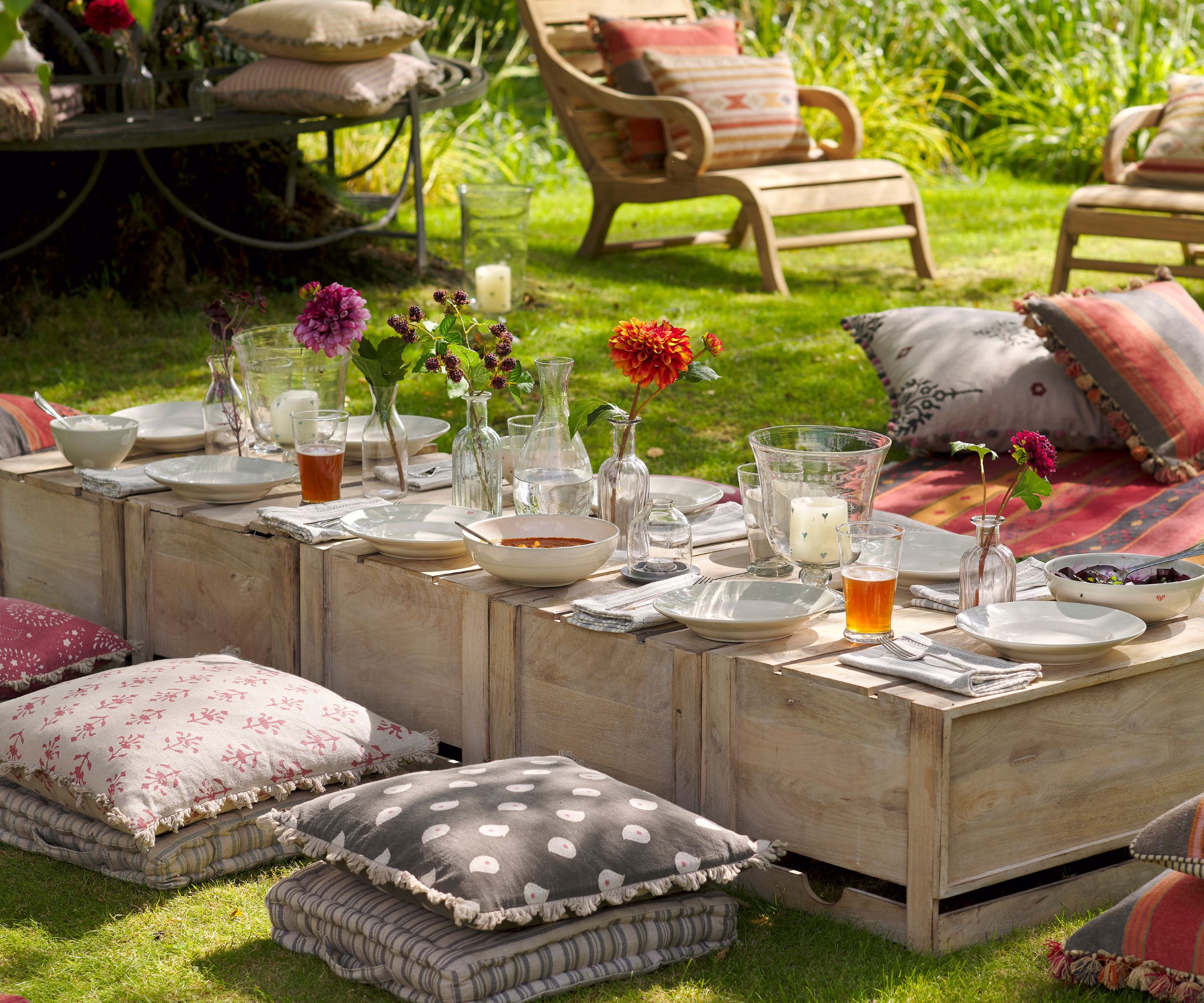 Garden picnic with wooden crates as tables and floor cushions by Susie Watson designs