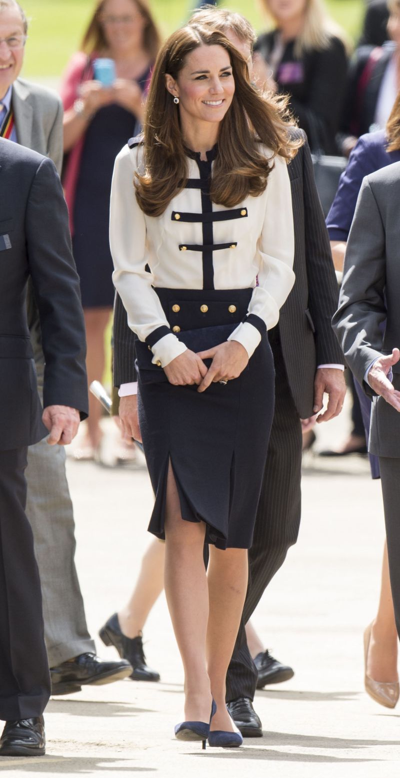 The Queen of recycling a great outfit, she rewore this military-inspired gold button blouse and navy skirt combination designed by Alexander McQueen for a daytime outing.