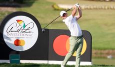 Rory McIlroy hits a tee shot in front of an Arnold Palmer Invitational sign