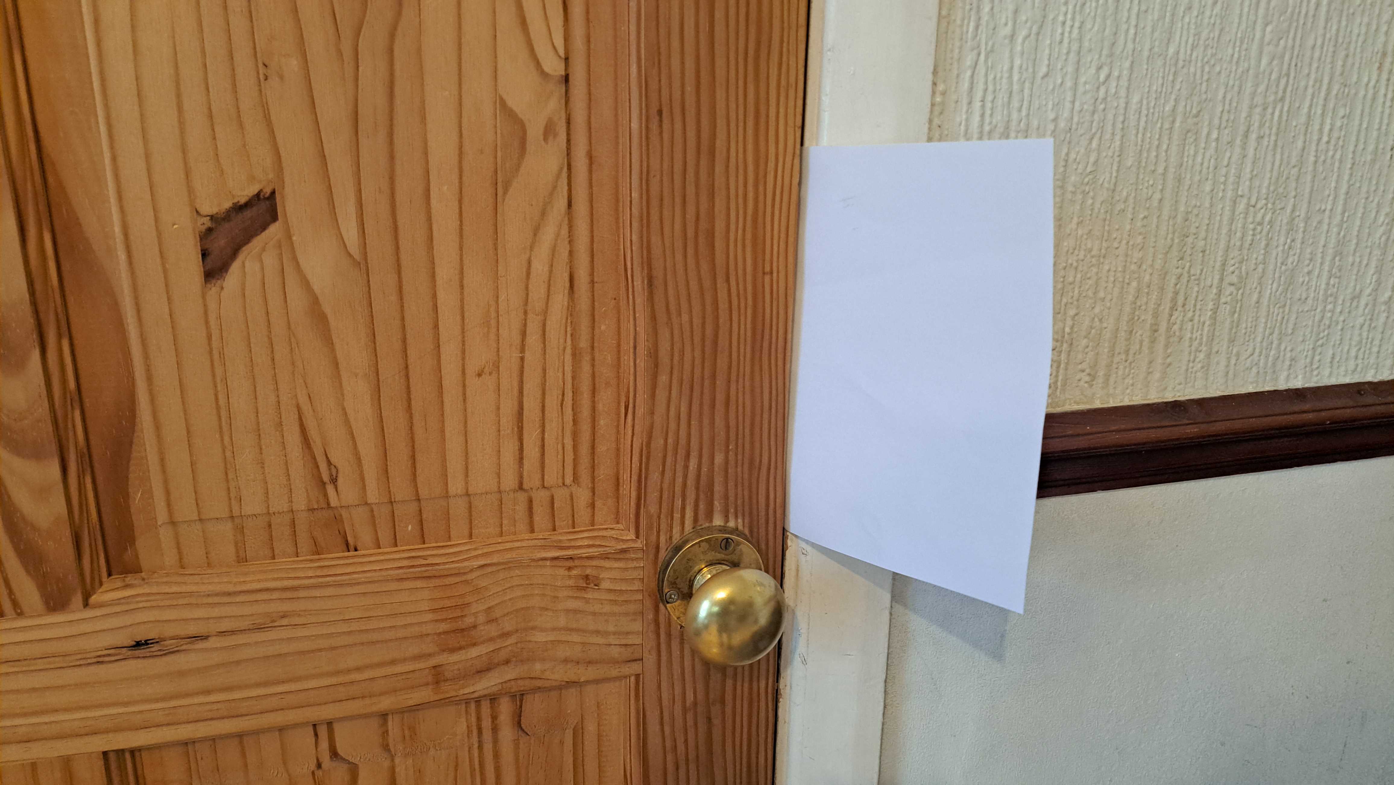 Wooden door with white paper to check for drafts