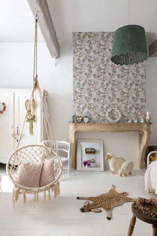 childrens room with white painted floors, wallpapered chimney breast and rattan swing seat
