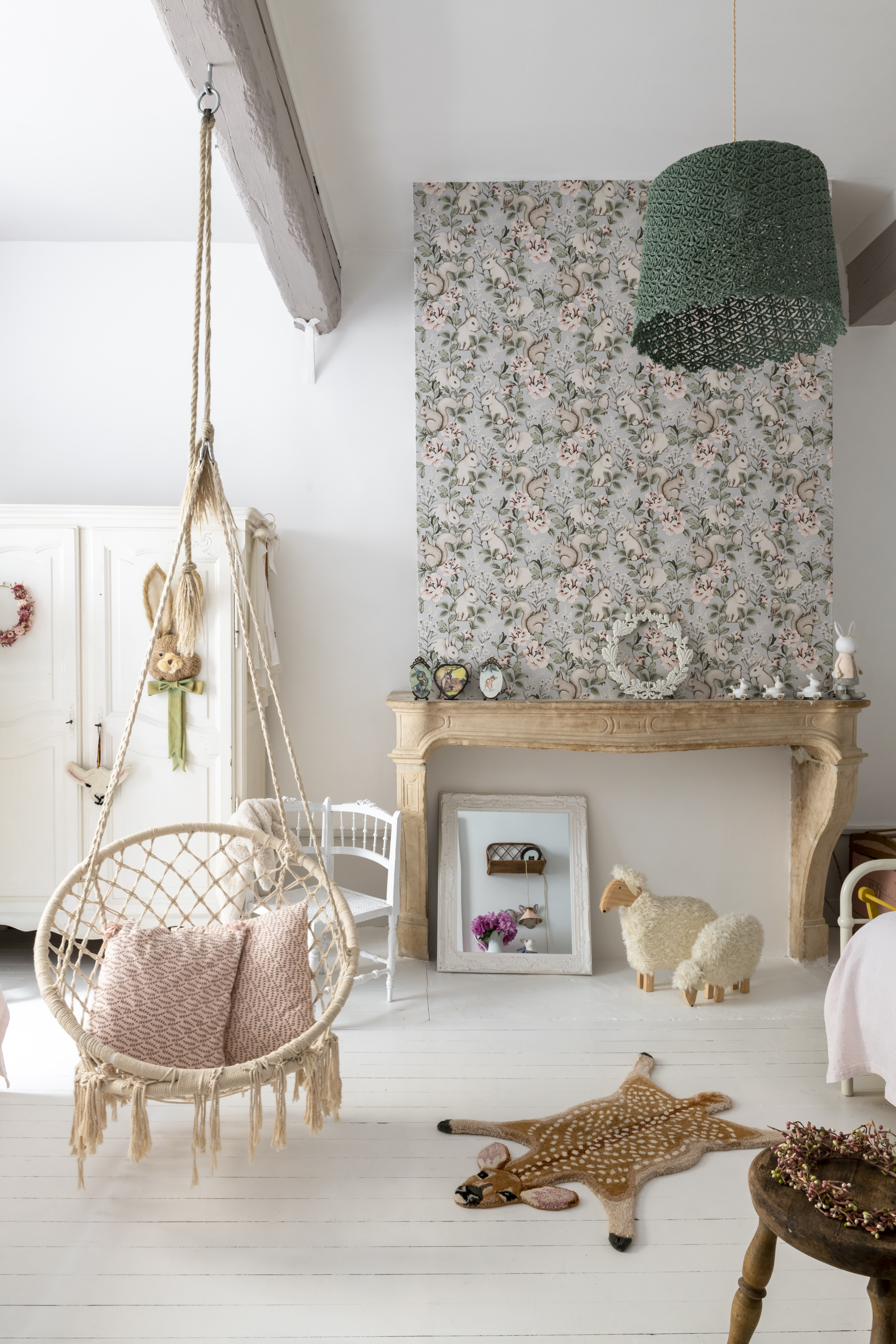chambre d'enfant avec sols peints en blanc, manteau de cheminée tapissé et balançoire en rotin