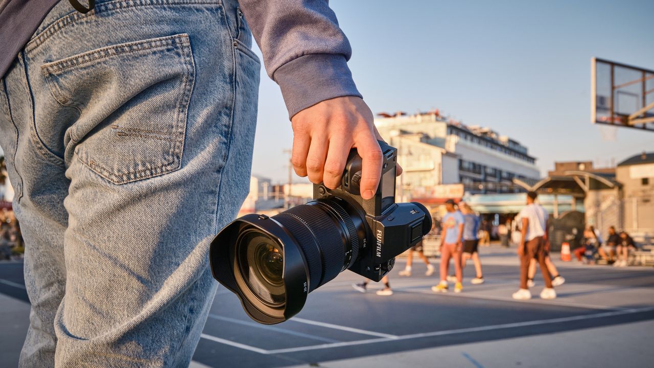 The Fujifilm GFX100 II camera being held against a golden hour scene