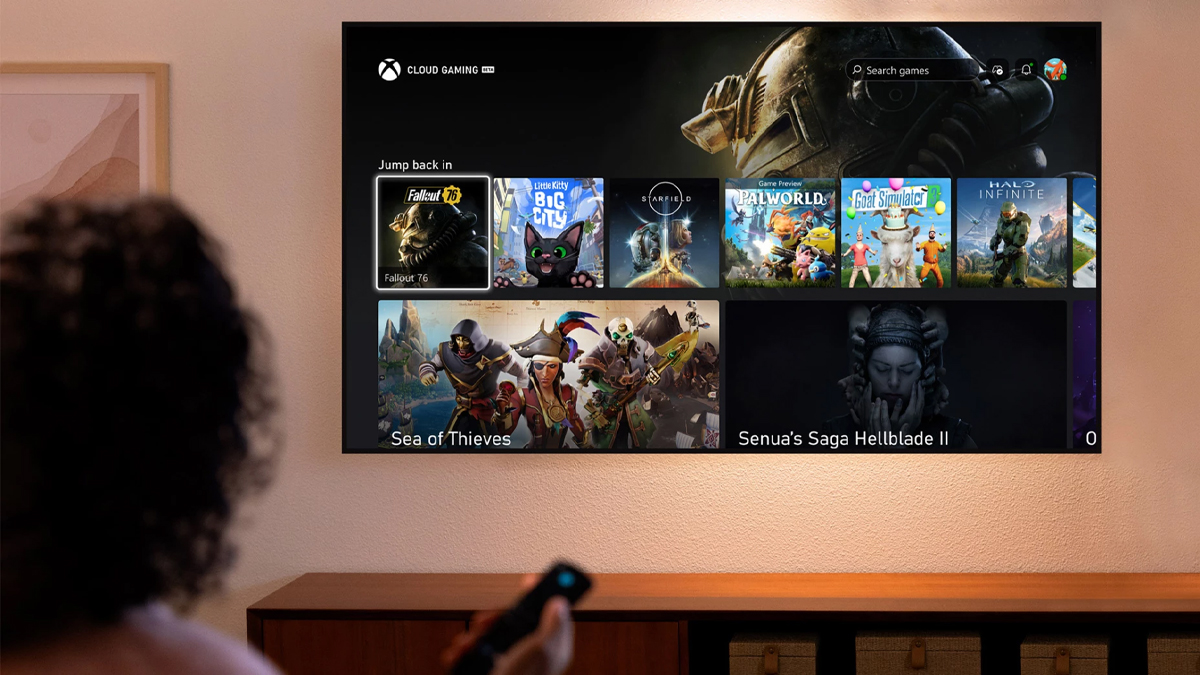 A person holding an Amazon Fire TV stick and navigating the Xbox Cloud Gaming app on a television.