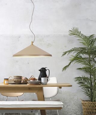 Grey concrete walls with wooden bench dining table and oversized sand colored pendant light