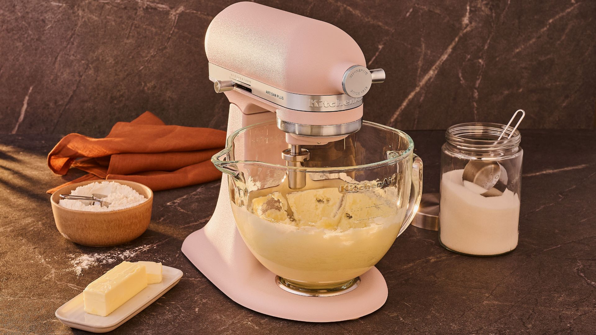The KitchenAid Artisan Plus Tilt-Head 4.7L Stand Mixer with ingredients around it