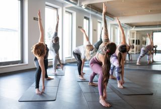 A bunch of people doing a yoga/pilates style class on yoga mats.