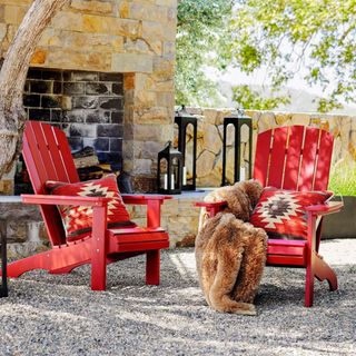 Classic Mahogany Adirondack Chairs against a stone wall. 