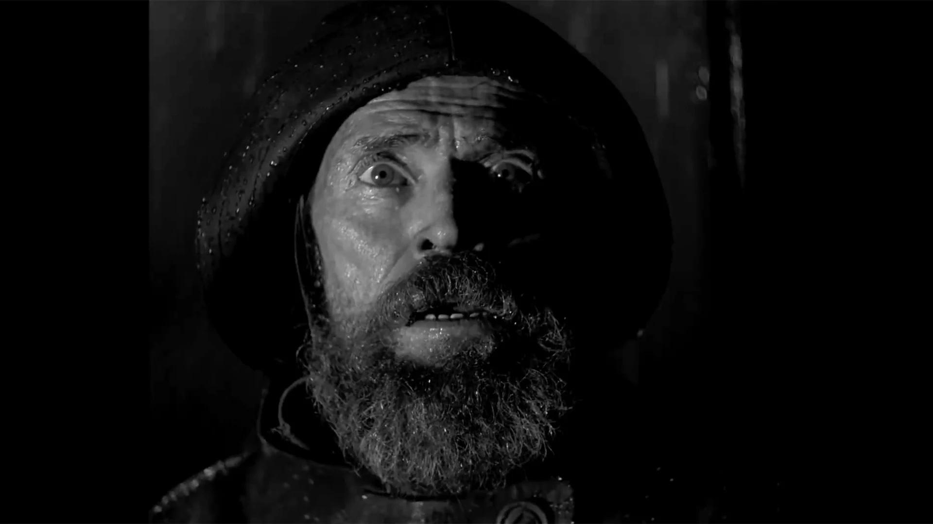 Willem Dafoe looking scared in black and white as seen in the film, The Lighthouse