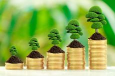 Stack of coins with growth sprout plant with fresh green nature blurred background, long term investment concept.