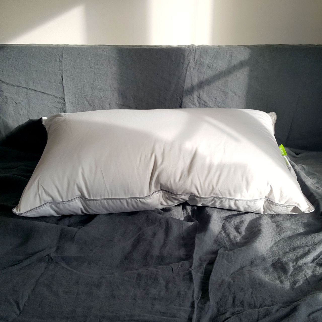 White scooms Hungarian Goose Down pillow with grey edge on a bed with grey bedlinen