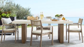 A Pomona Concrete & FSC table and chairs in a coastal garden