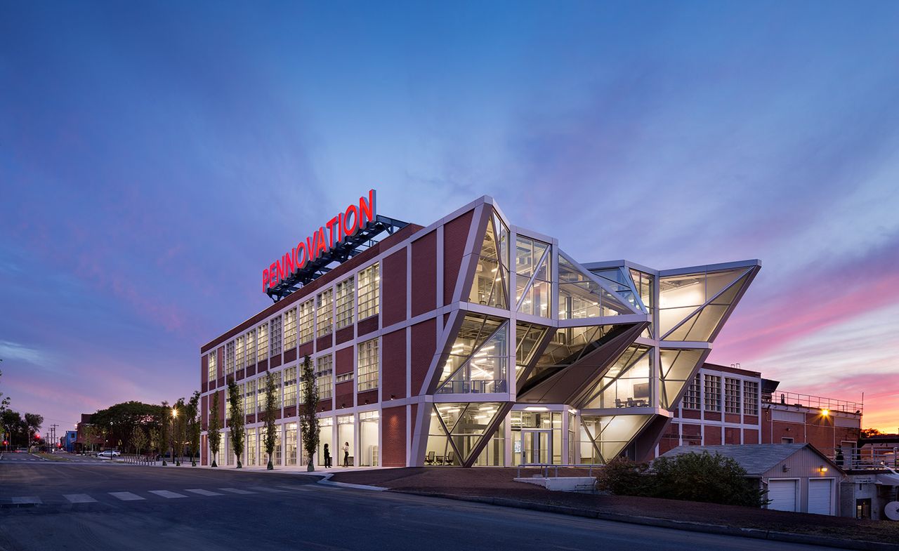 Angular, glass-panel building with a red &quot;Pennovation&quot; sign, at night