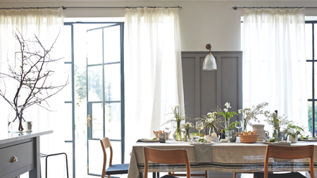 a dining room with sheer curtains covering the doors