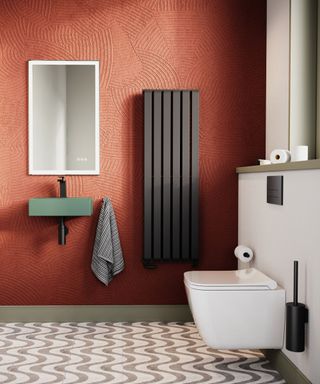 Bold and contemporary small bathroom featuring textured terracotta walls, a sleek green wall-mounted sink, and a modern black radiator.