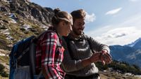 Man and woman hiking, looking at watch