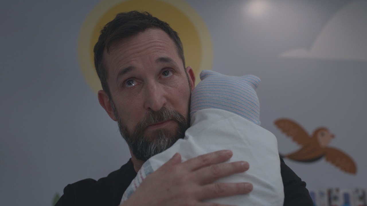 Noah Wyle holding a baby on The Pitt.