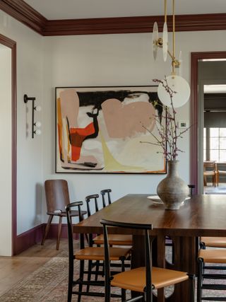 Dining room with neutral walls, burgundy brown trim and wood floor and furnishing