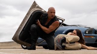 Vin Diesel protects a woman with a car door in Fast X