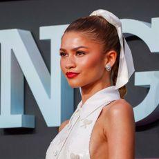 Zendaya wears a white Thom Browne dress with a matching hair ribbon on the Challengers London premiere red carpet