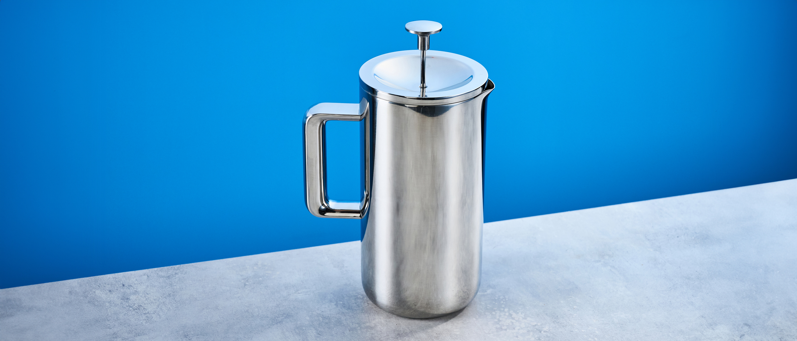 the aarke french press in silver showing the french press filter system, lid, spout, and inside photographed against the blue tom's guide background