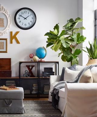 Bright industrial living room with a white couch, black steel dresser, plants, and a gallery wall