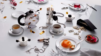 Christofle silver collection on white table cluttered with food and drink