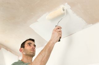 decorator painting a ceiling that has been newly plastered