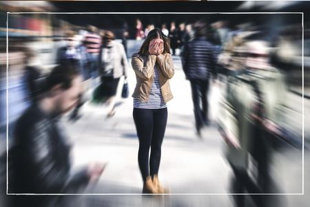 woman experiencing panic attack symptoms in busy place surrounded by people 