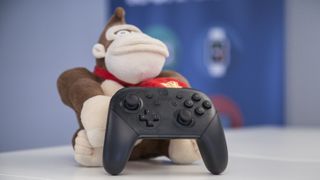 Bästa Nintendo Switch-kontroller: En svart Nintendo Switch Pro Controller står upplutad mot ett Donkey Kong-gosedjur på ett vitt skrivbord.