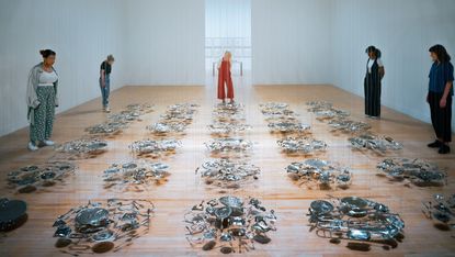 Thirty household items flattened into discs and suspended in a sea of silver