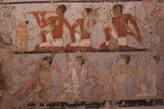 An orchestra is seen playing in this painting. A variety of wind and string instruments are used by the different musicians. Archaeologists say that there is a monkey (not seen) dancing in front of this orchestra.