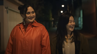 Lily Gladstone and Kelly Marie Tran smiling while they walk at night in The Wedding Banquet