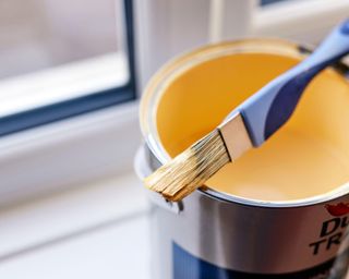 yellow paint can and brush by window