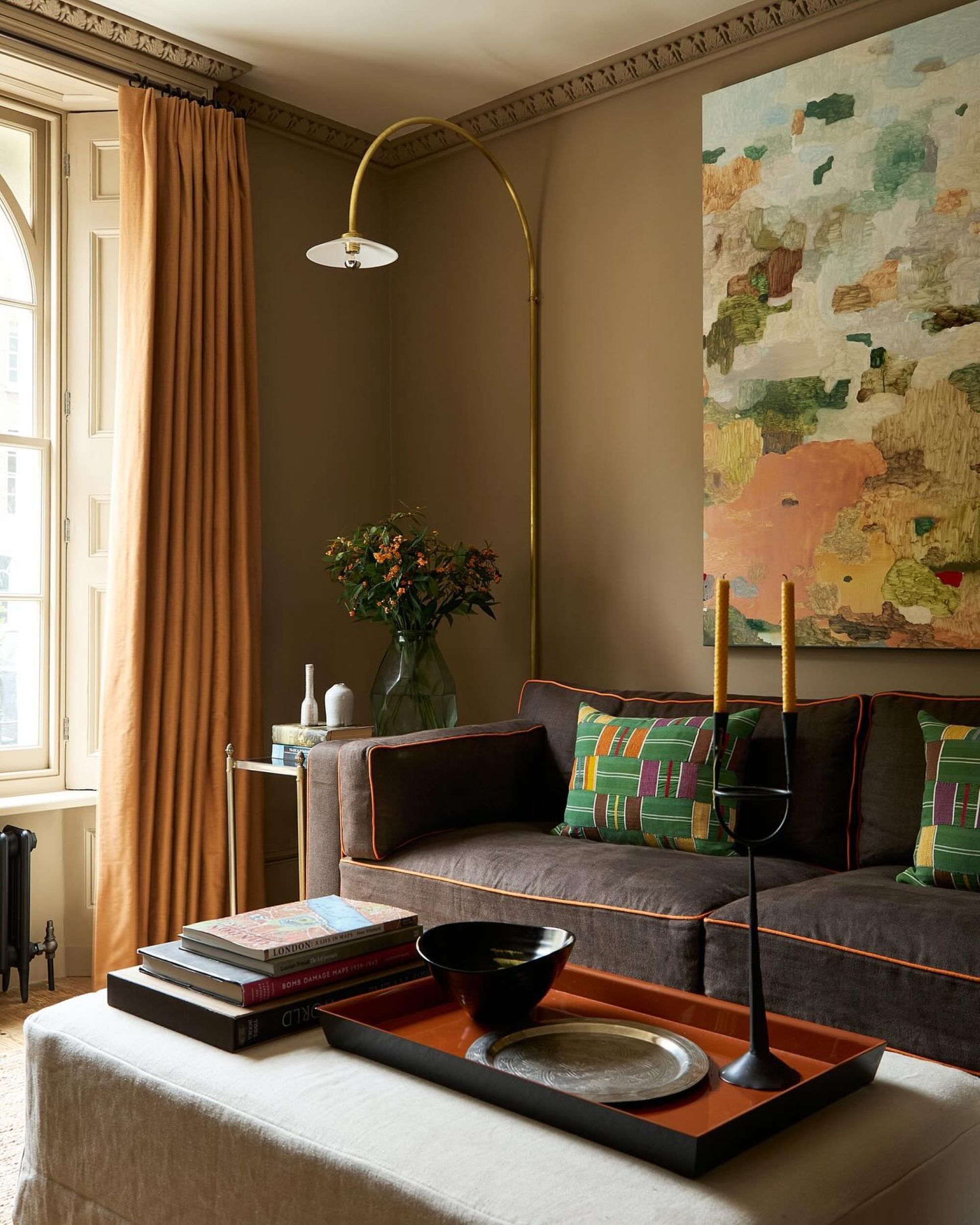 living room with a dark brown couch, light brown walls and green pillows