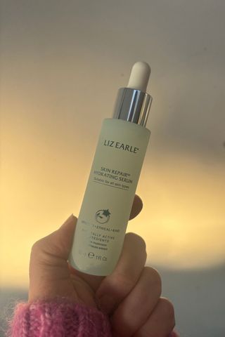 a hand holding the liz earle serum