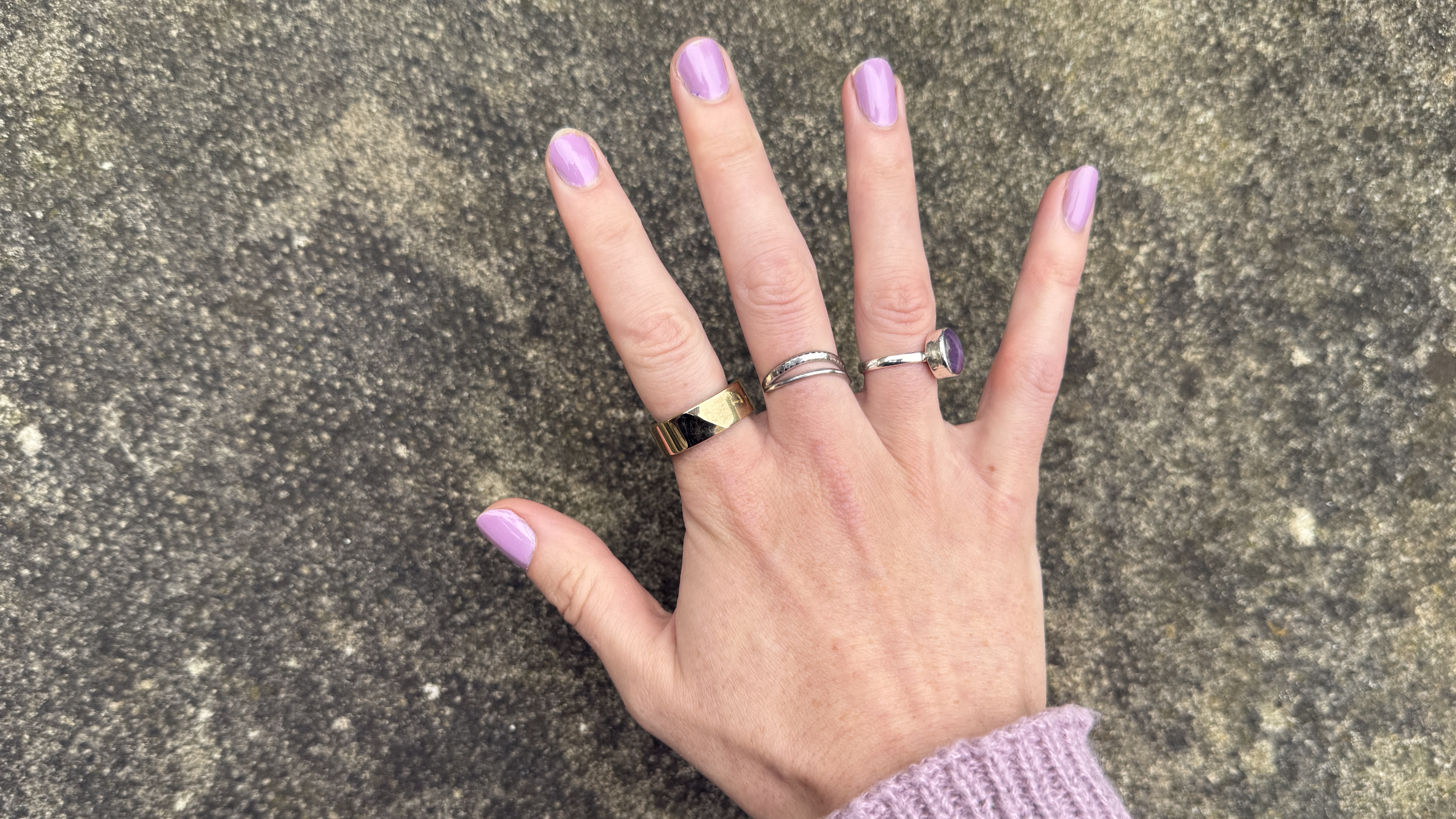 The Luna Ring 2 worn on a woman's hand against a concrete surface.