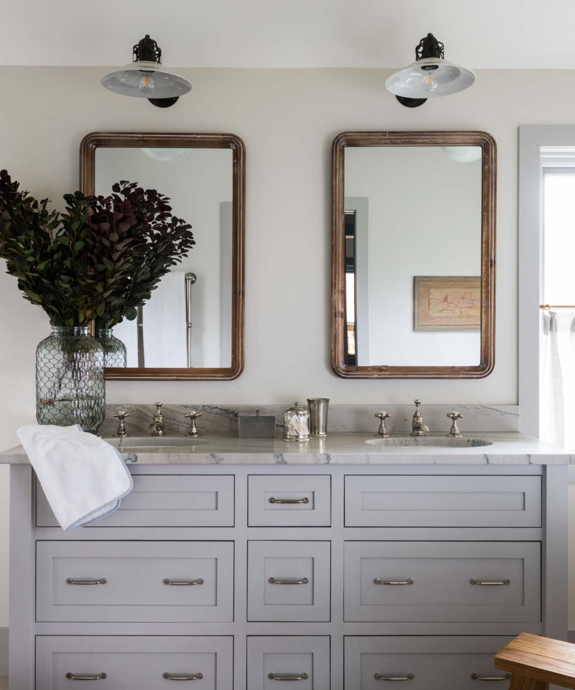 A white bathroom with a light blue vanity and bronze mirrors