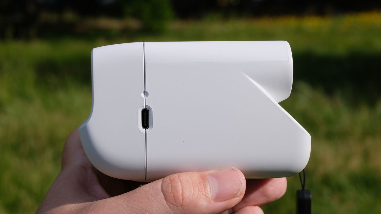 Photograph of man's hand holding Polaroid Go Gen 3 camera in white, side view showing USB-C port