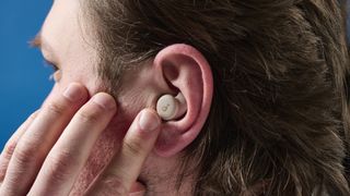 A photo of the Soundcore Sleep A20 earbuds in ear being tapped.