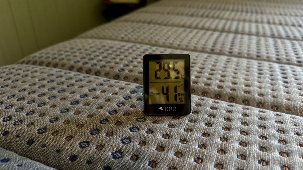 A thermostat showing 29.5 degrees celsius on the surface of Brooklyn Bedding Copperflex Memory Foam Mattress. The cover is grey with navy and bronze speckles.