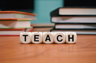 A desk with letter cubes on it spelling out the word "teach."