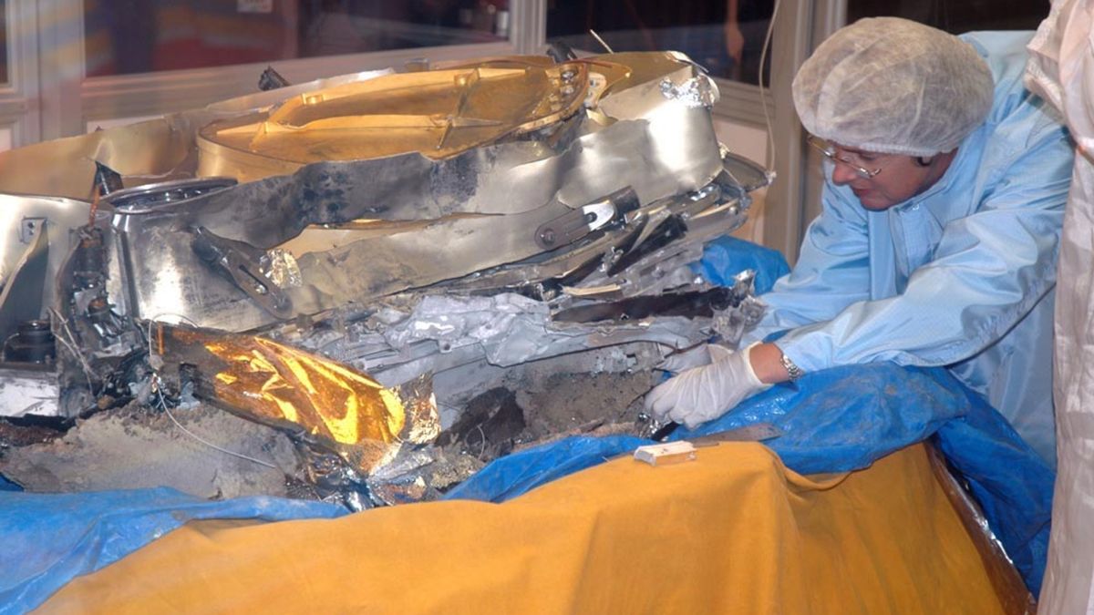 Um cientista com equipamento de proteção tentando proteger amostras de vento solar da espaçonave Genesis acidentada