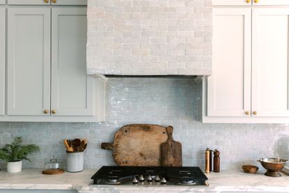 Image of a kitchen with glazed tiles and a rustic wooden cutting board