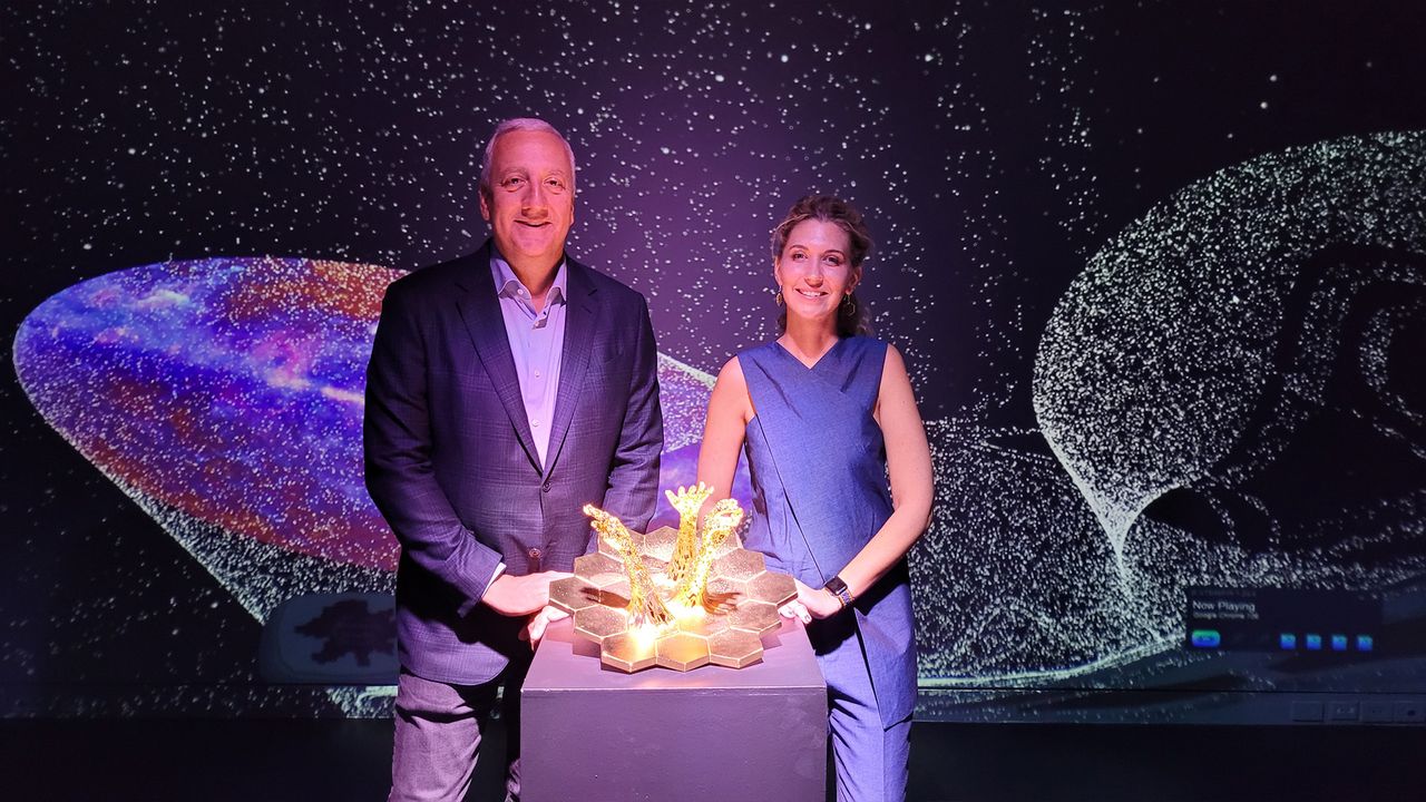 Conceptual artist Ashley Zelinskie and retired NASA astronaut Mike Massimino with the "Exploration JWST" artwork on display at the "Unfolding the Universe: First Light" exhibit.