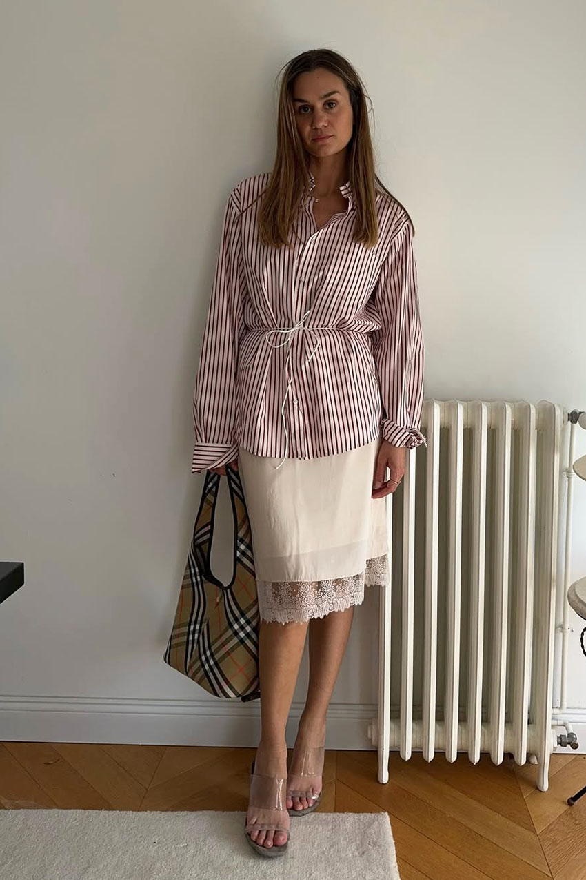 a woman wearing a red and white striped shirt, white lace-trim skirt, plaid bag, and clear sandals