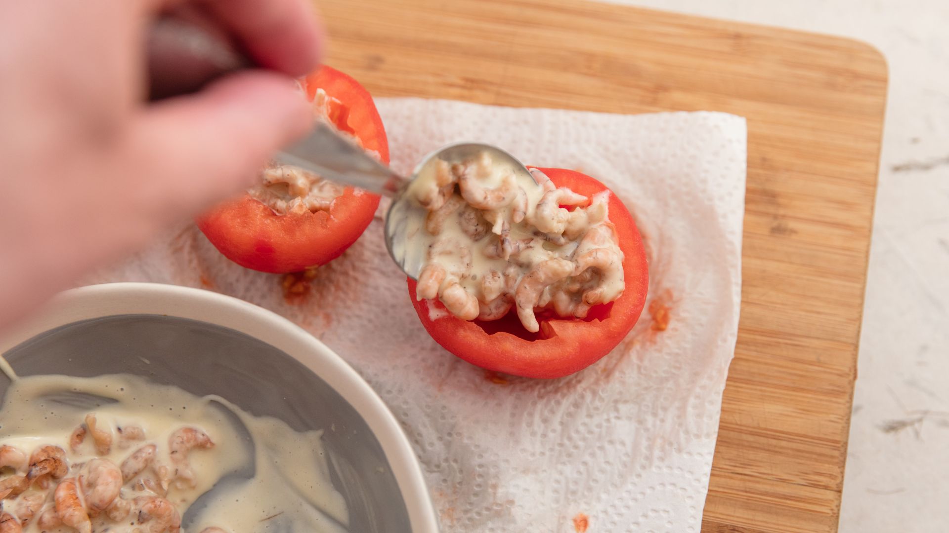 Person preparing stuffed tomatoes on a chopping board