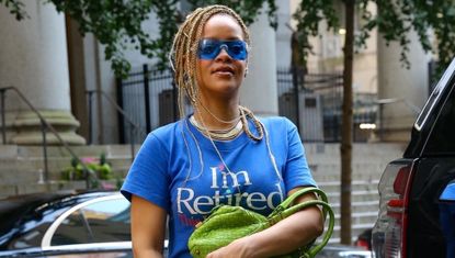 Rihanna wearing a blue I'm retired t shirt dress by connor ives with a green bottega veneta bag while walking in new york city